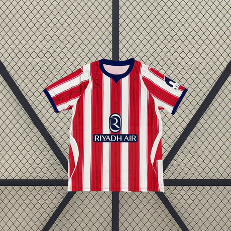 Vista frontal extendida de la camiseta Atlético de Madrid 26-27 local, con rayas rojas y blancas, detalles azules y paneles laterales claros