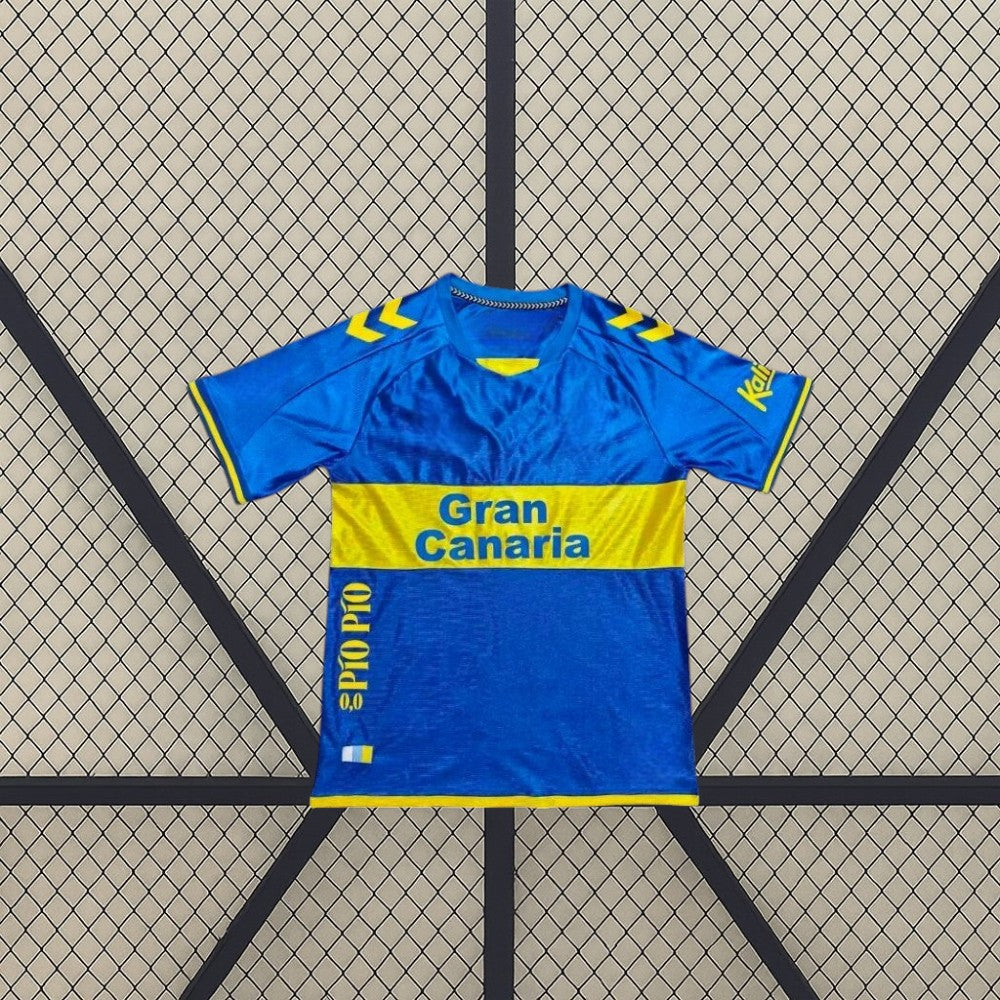 Vista frontal extendida de la camiseta Las Palmas 26-27 visitante, con banda amarilla en el pecho y detalles amarillos en hombros y puños