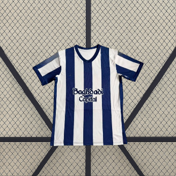 Vista frontal extendida de la camiseta Real Sociedad 26-27 local con franjas blancas y azul marino, puños oscuros y paneles laterales