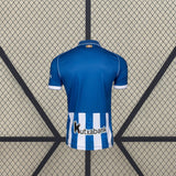 Vista trasera de la camiseta Alavés 26-27 local en color azul, con panel inferior de rayas verticales azules y blancas