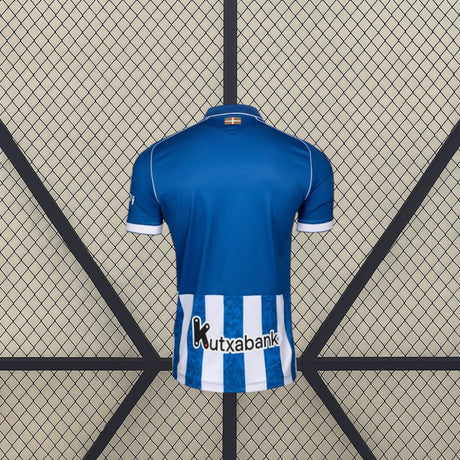 Vista trasera de la camiseta Alavés 26-27 local en color azul, con panel inferior de rayas verticales azules y blancas