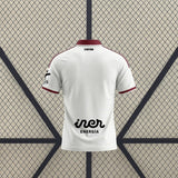 Vista trasera de la camiseta Albacete 26-27 local blanca con cuello granate, detalles lineales en los hombros y ribetes granates en mangas
