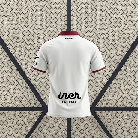 Vista trasera de la camiseta Albacete 26-27 local blanca con cuello granate, detalles lineales en los hombros y ribetes granates en mangas