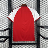 Vista trasera de la camiseta Arsenal 26-27 local en rojo, con mangas blancas, paneles granate en los hombros y puños texturizados