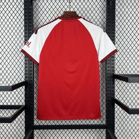 Vista trasera de la camiseta Arsenal 26-27 local en rojo, con mangas blancas, paneles granate en los hombros y puños texturizados