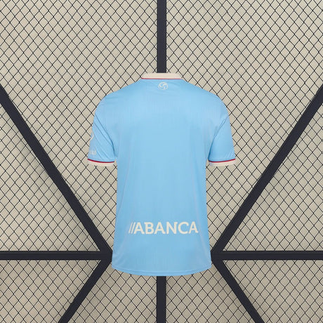 Vista trasera de la camiseta Celta de Vigo 26-27 local en color azul celeste, con diseño liso y detalle bajo el cuello