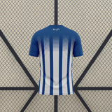 Vista trasera de la camiseta Huelva 26-27 Local con franjas verticales azules y blancas y parte superior azul