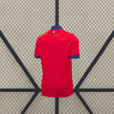 Vista trasera de la camiseta Osasuna 26-27 local en color rojo, con cuello y puños azules y pequeño detalle gráfico bajo el cuello