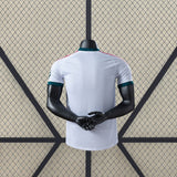 Vista trasera de la camiseta R.M. 26-27 Local Player Version blanca con remates verde oscuro en cuello y mangas y detalles rosas