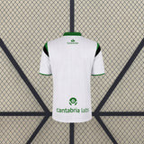 Vista trasera de la camiseta Racing Santander 26-27 local blanca con cuello verde, ribetes verdes en las mangas y paneles negros