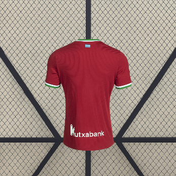 Vista trasera de la camiseta Real Sociedad 26-27 tercera equipación en rojo con manga corta y detalles verdes y blancos en cuello y puños