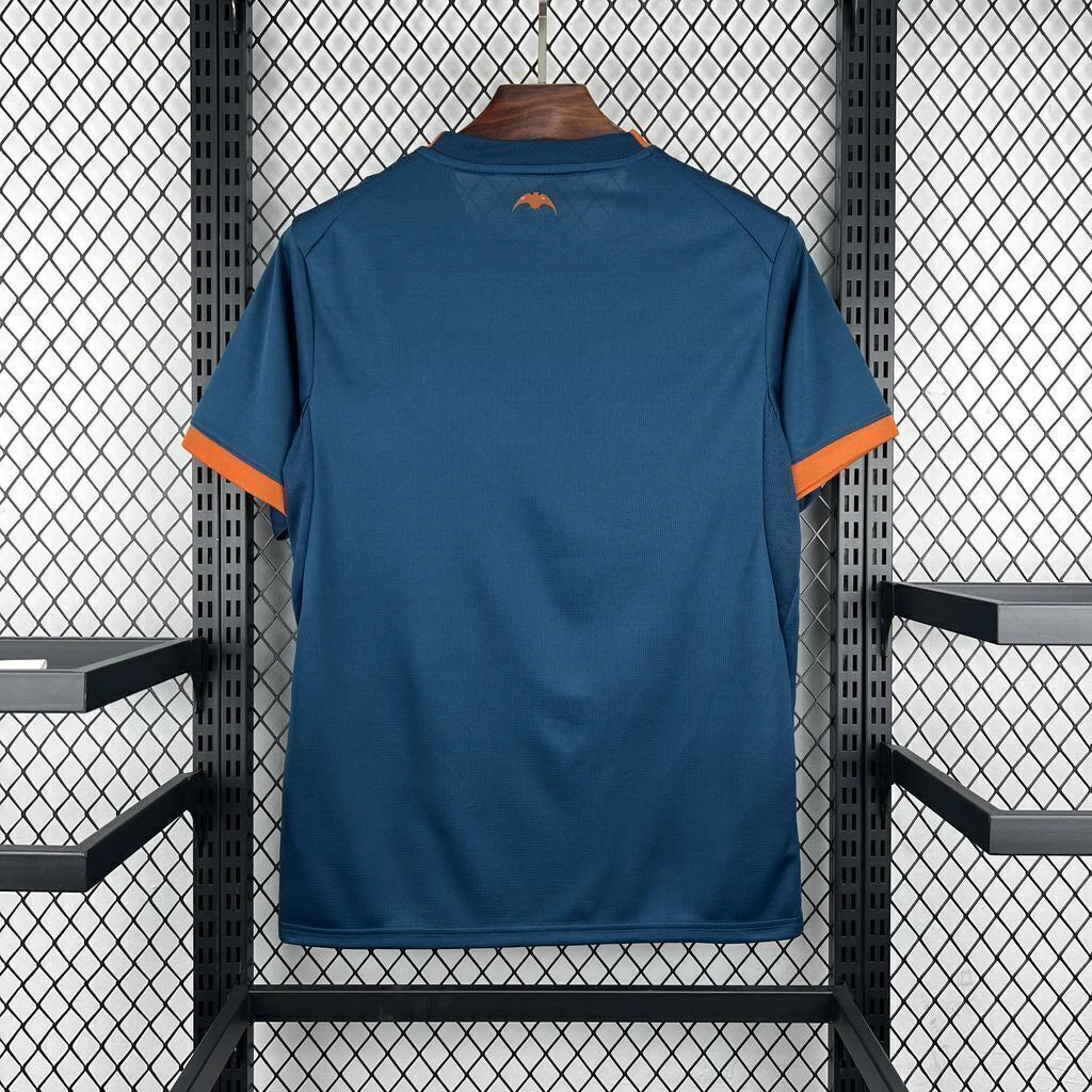 Vista trasera de la camiseta Valencia 26-27 visitante en azul oscuro, con puños naranjas y pequeño detalle naranja bajo el cuello