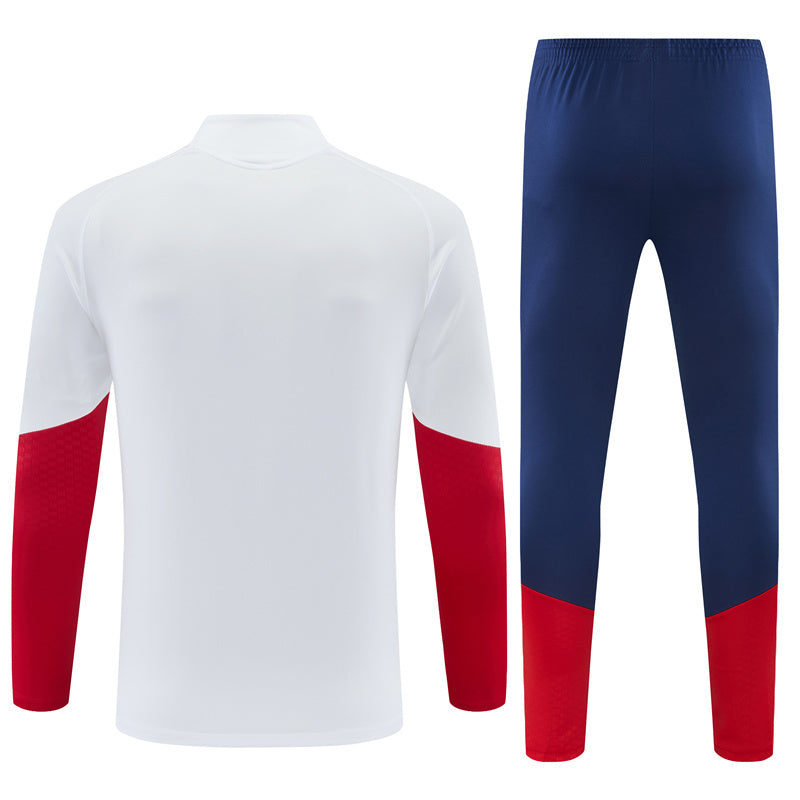 Vista trasera del Chándal España 26-27 media cremallera con chaqueta blanca y pantalón azul marino con bajos rojos