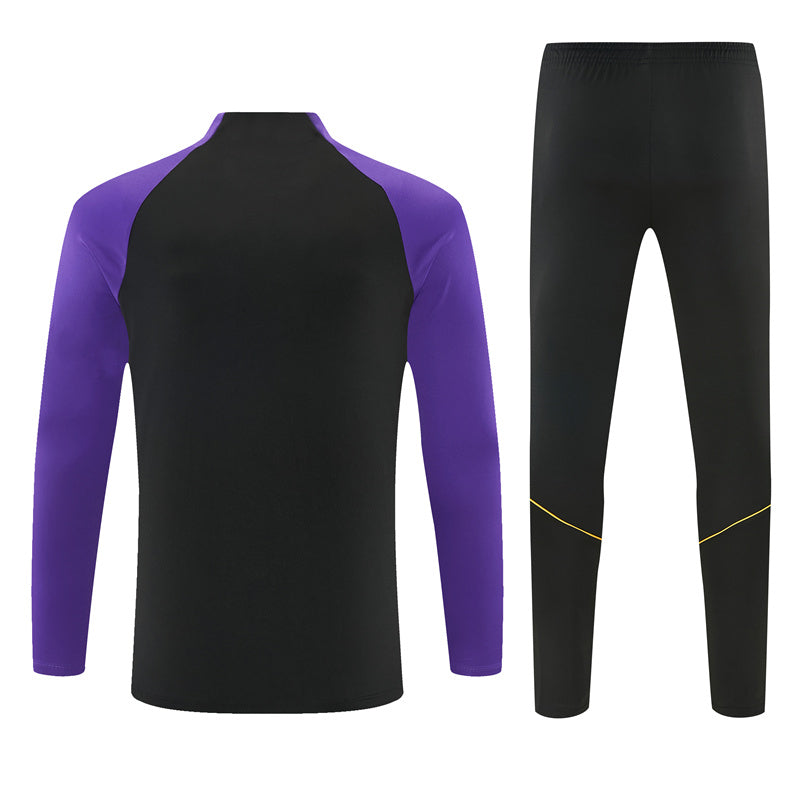 Vista trasera del chándal Barcelona 26-27 Modelo 2 con parte superior negra de mangas moradas y pantalón negro