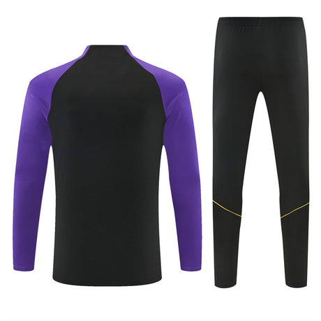 Vista trasera del chándal Barcelona 26-27 Modelo 2 con parte superior negra de mangas moradas y pantalón negro