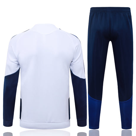 Vista trasera del chándal Boca Juniors 26-27 con chaqueta blanca, paneles azul marino en las mangas y pantalón azul marino con bajos azules