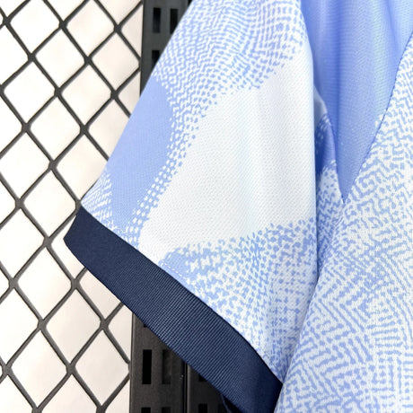Detalle de la manga corta con ribete azul marino y patrón azul claro de la camiseta Ajax 26-27 tercera equipación