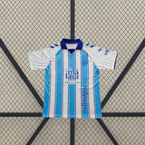 Camiseta Málaga 26-27 local frontal con franjas verticales azul celeste y blanco