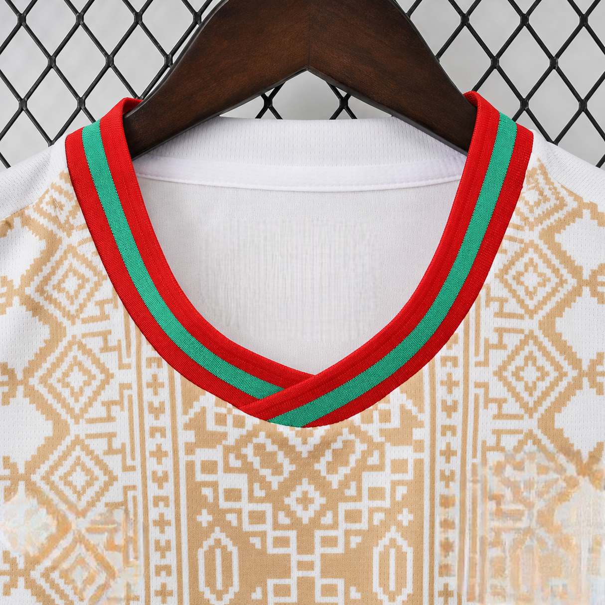 Detalle del cuello de la camiseta Marruecos 26-27 visitante con acabados en rojo y verde y patrón dorado