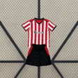 Equipación Athletic de Bilbao 26-27 local niño vista frontal con camiseta de franjas rojas y blancas y pantalón negro