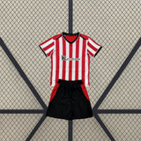 Equipación Athletic de Bilbao 26-27 local niño vista frontal con camiseta de franjas rojas y blancas y pantalón negro