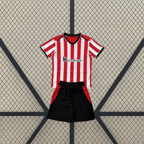 Equipación Athletic de Bilbao 26-27 local niño vista frontal con camiseta de franjas rojas y blancas y pantalón negro